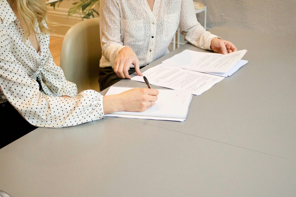 Two women signing legal contracts.