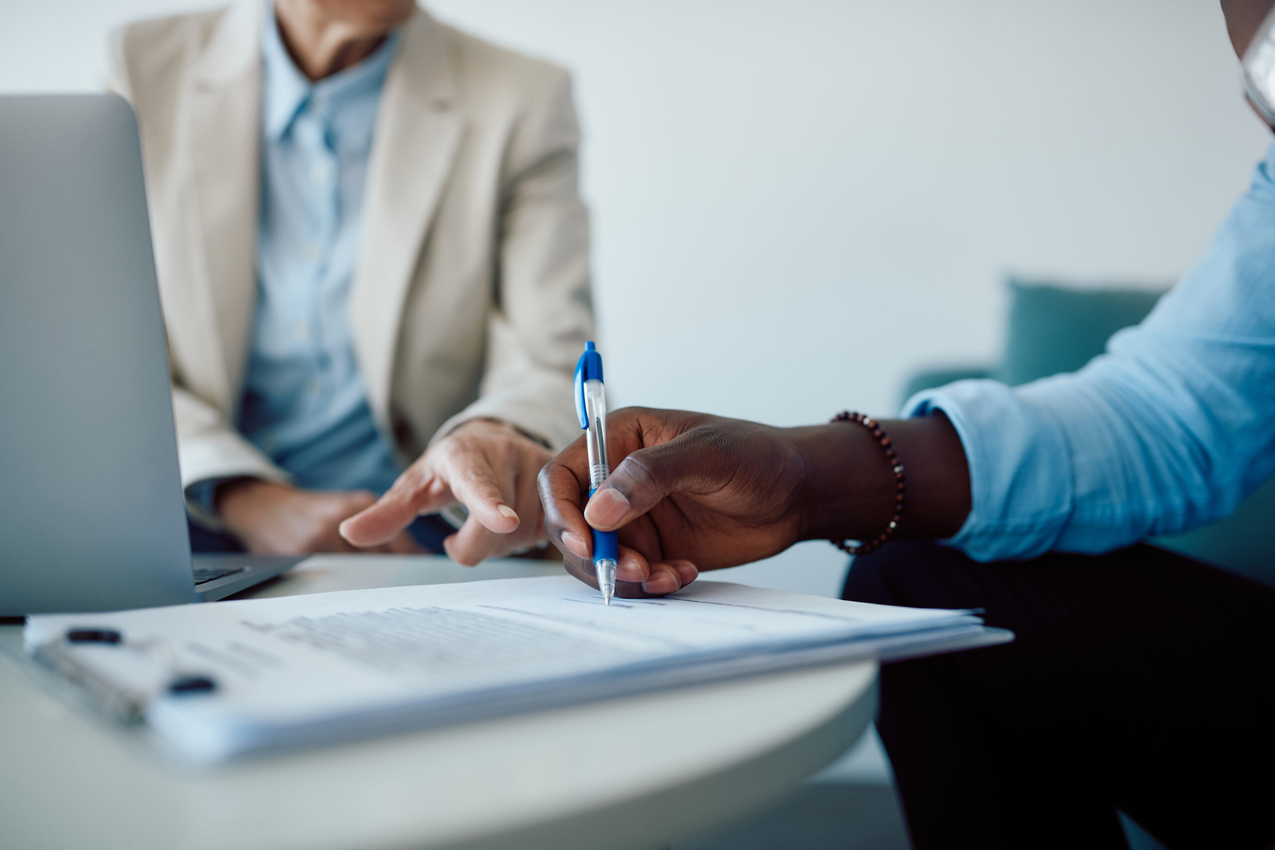 Close up of man signing a contract with insurance agent in the office.